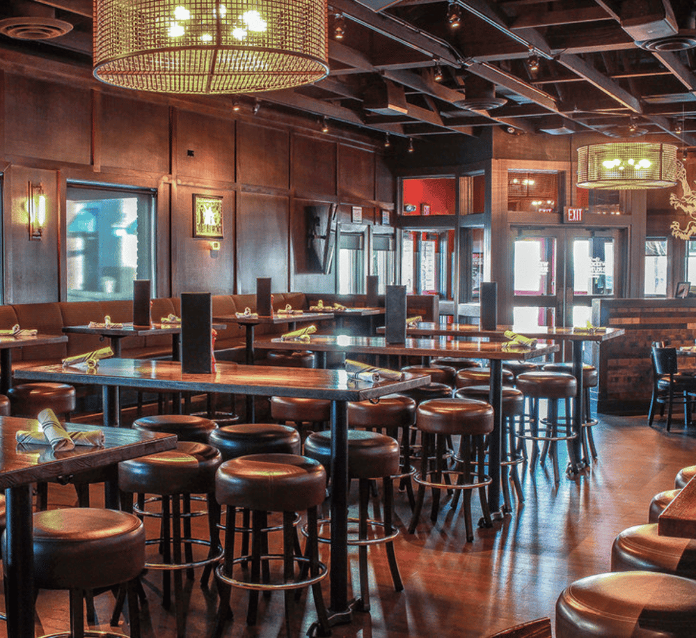 Cozy restaurant interior with wooden decor, ambient lighting, and seating for dining and social gatherings.