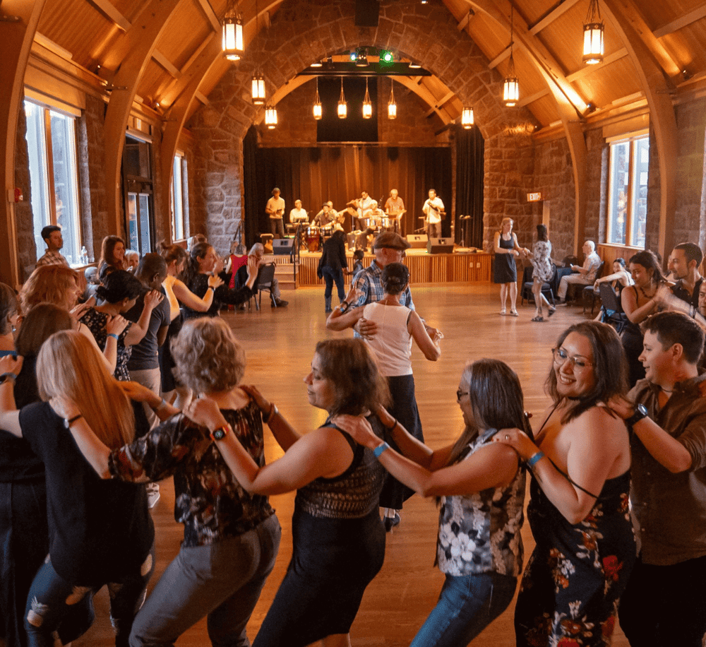 Dancing guests at a live music event in a rustic venue with stone walls and warm lighting.