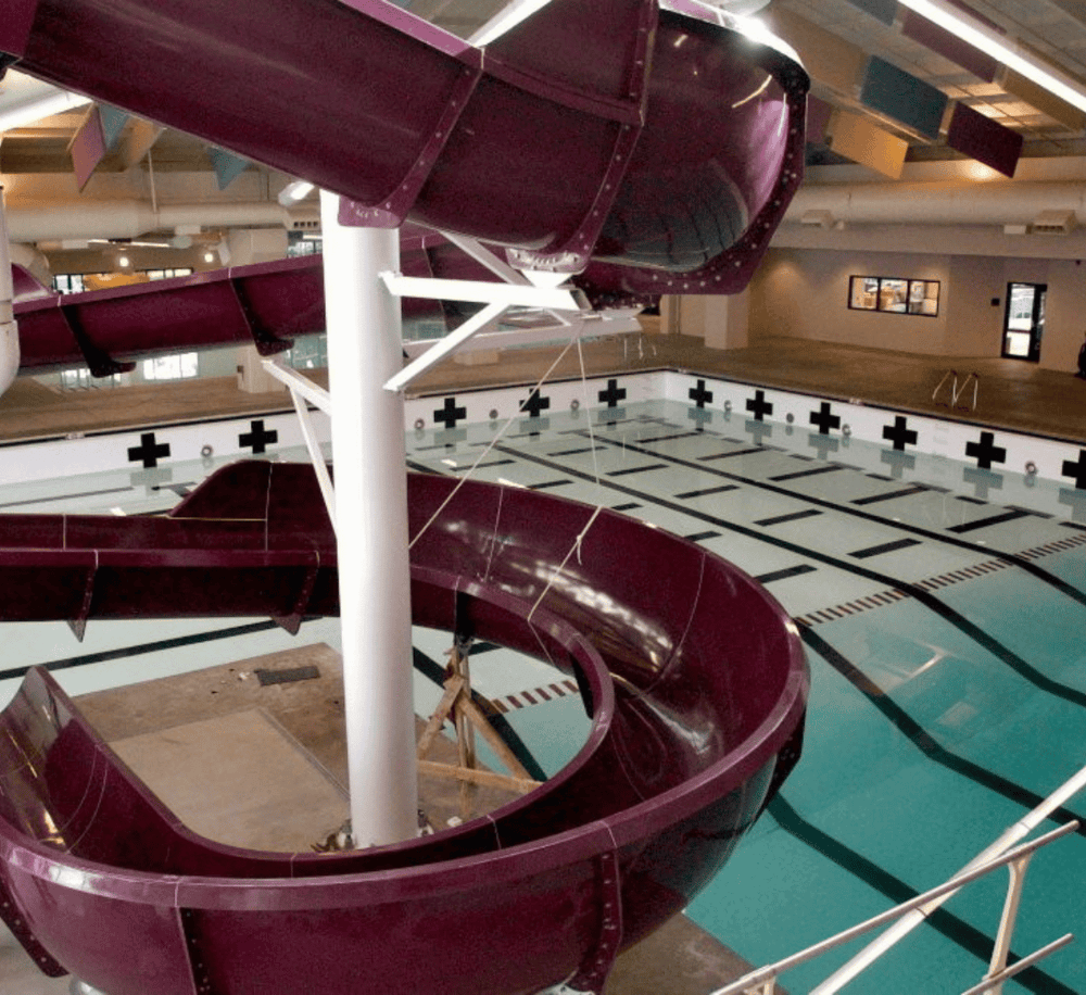 Water park with twisting water slide and swimming pool, indoor recreational facility, family fun activities.