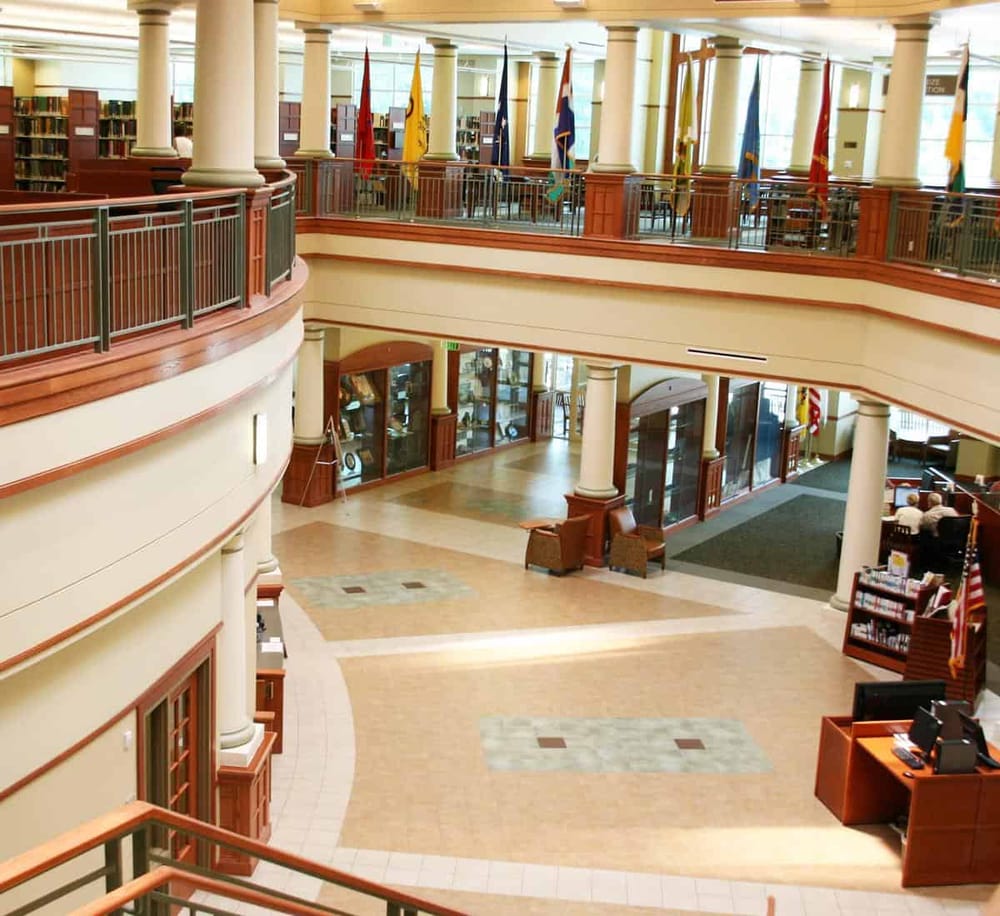 Quiet library interior with multiple bookcases and flags, ideal for reading or study.