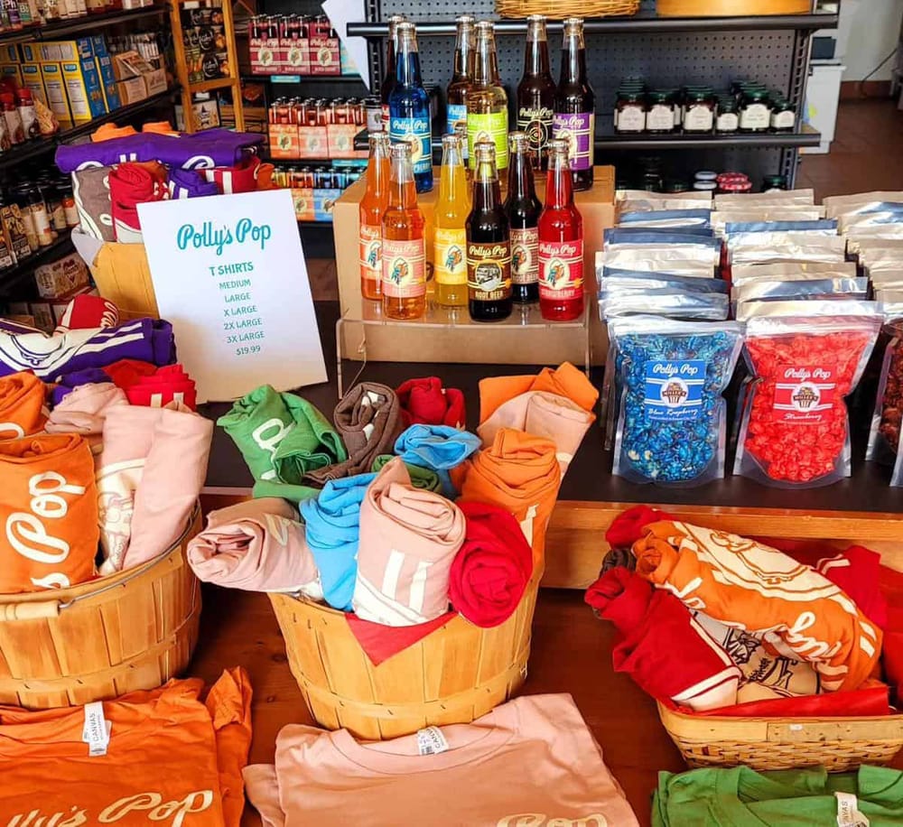 Authentic Polly's Pop t-shirts, drinks, and souvenirs display at a retail store.