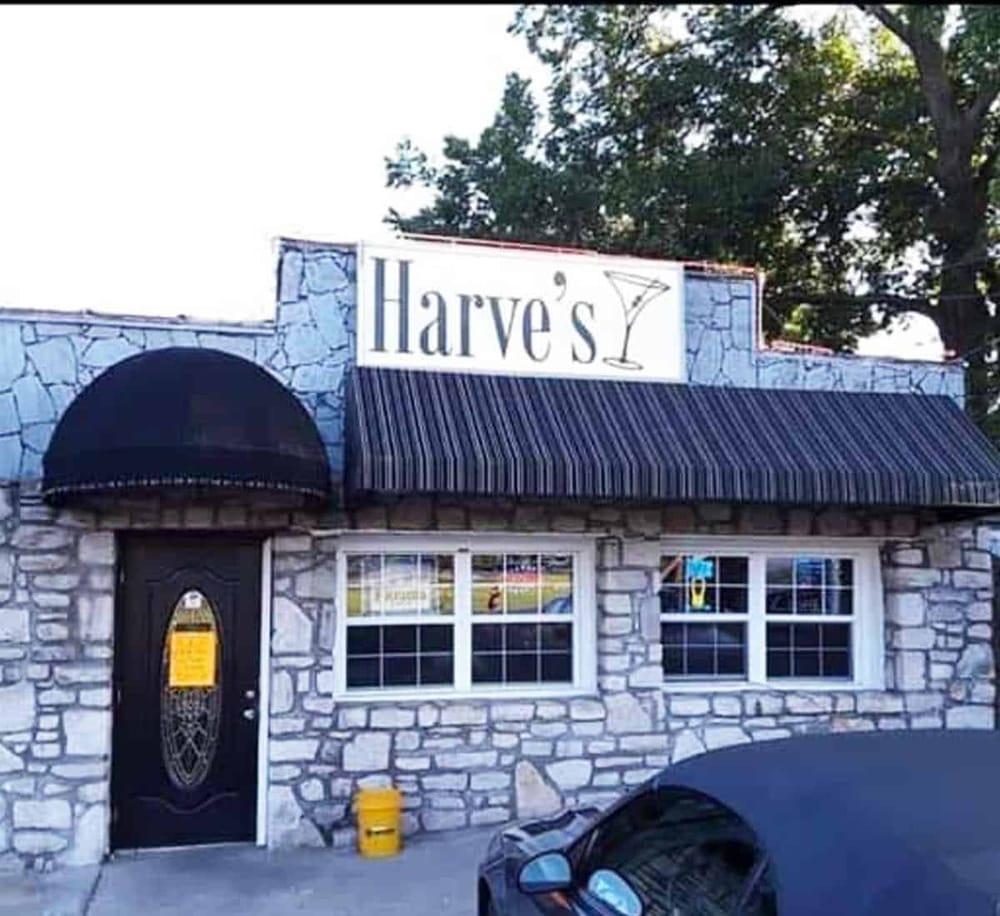 Elegant stone facade restaurant with striped awning, inviting outdoor patio, and welcoming signage.