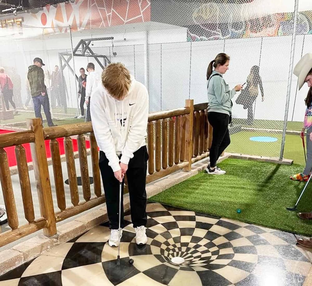 1. Indoor mini golf course at QuestForDirections with people enjoying game.
