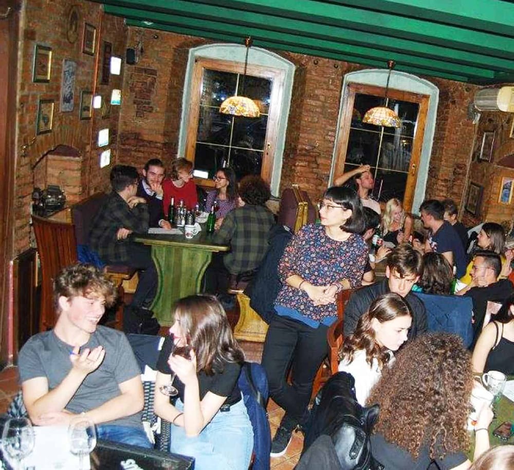 A lively cafe with young people socializing, surrounded by rustic brick walls and cozy lighting.