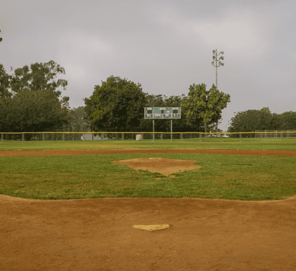 Baseball field with trees and scoreboard, overcast sky, for sports and outdoor recreation SEO.