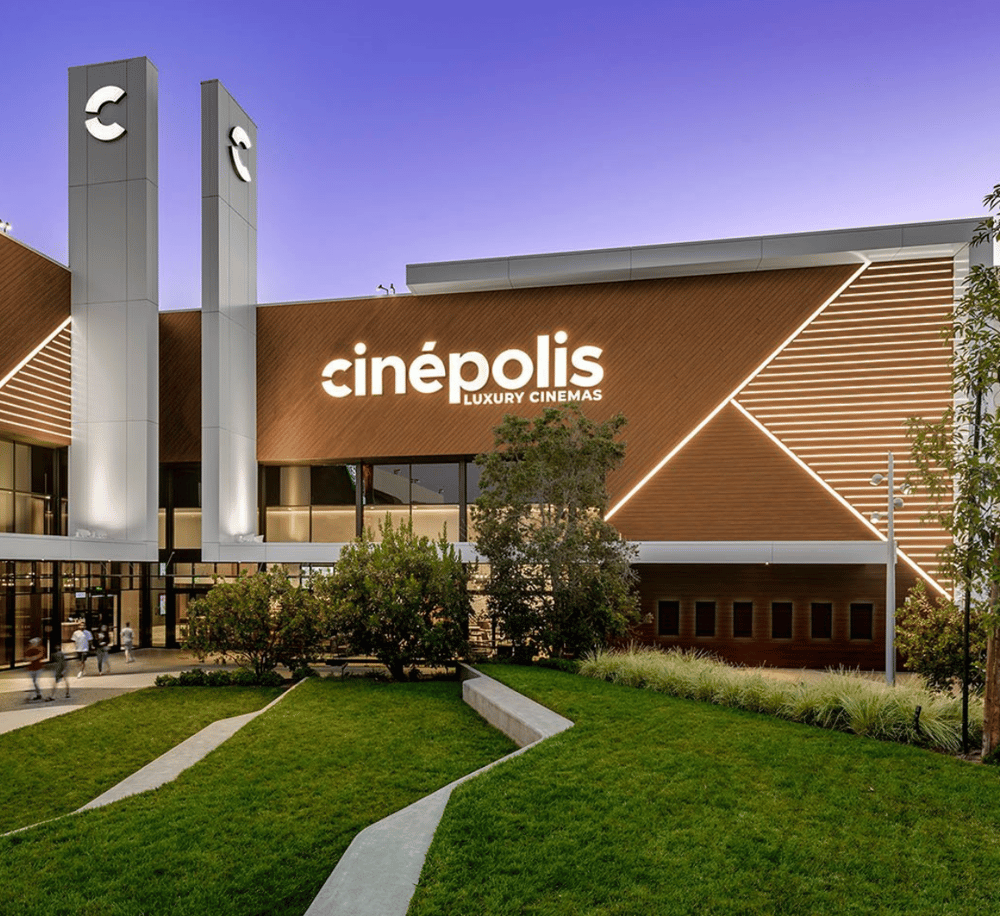 Modern luxury cinema theater at dusk with "Cinépolis" signage, contemporary architectural design, and landscaped surroundings.