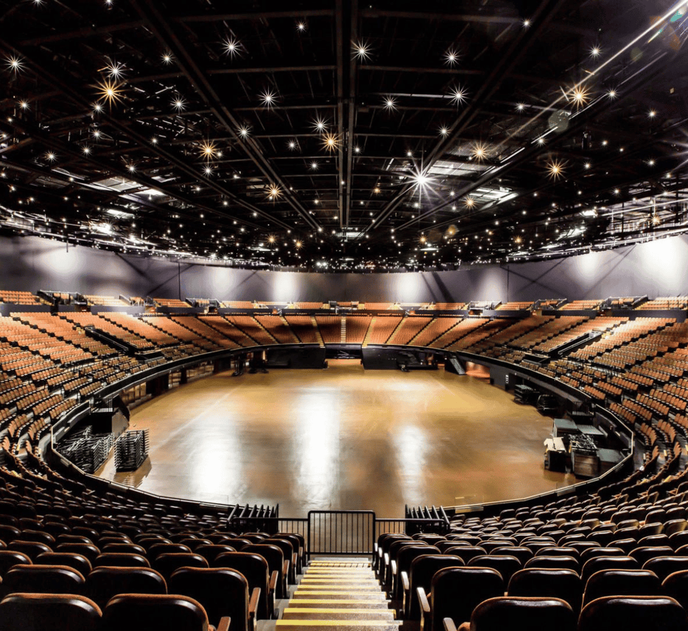 Indoor concert hall with circular seating and stage, modern design, perfect for live performances.