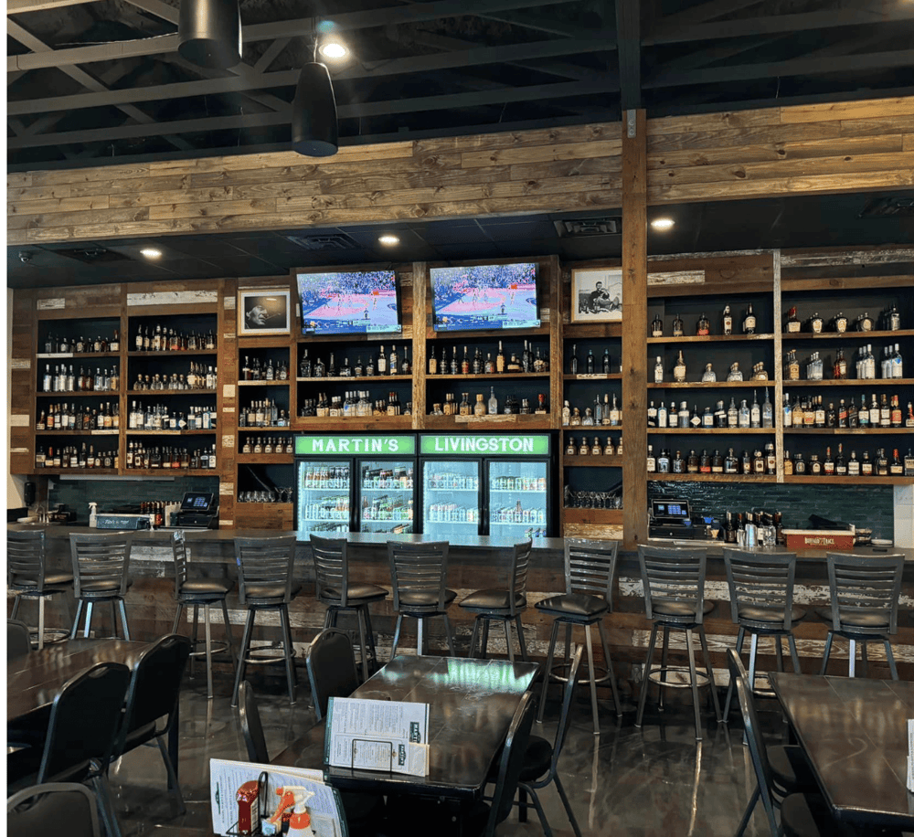 Whiskey bar interior with bottles on shelves, TVs, and seating area at QuestForDirections.