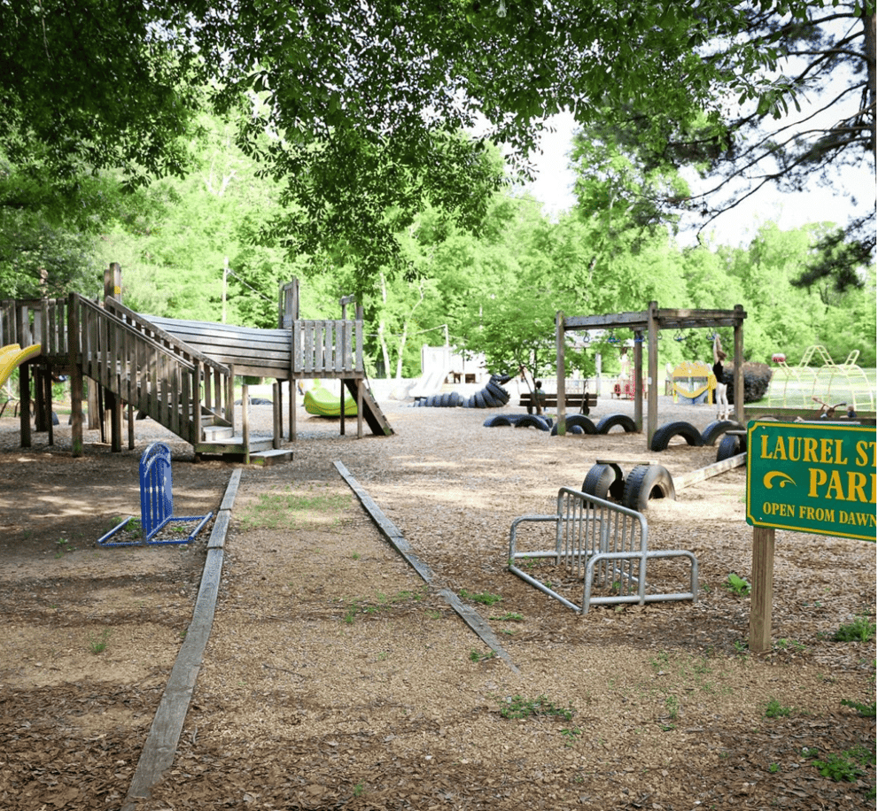 Wooden playground with slides and swings in Laurel Street Park, perfect for children's outdoor activities.