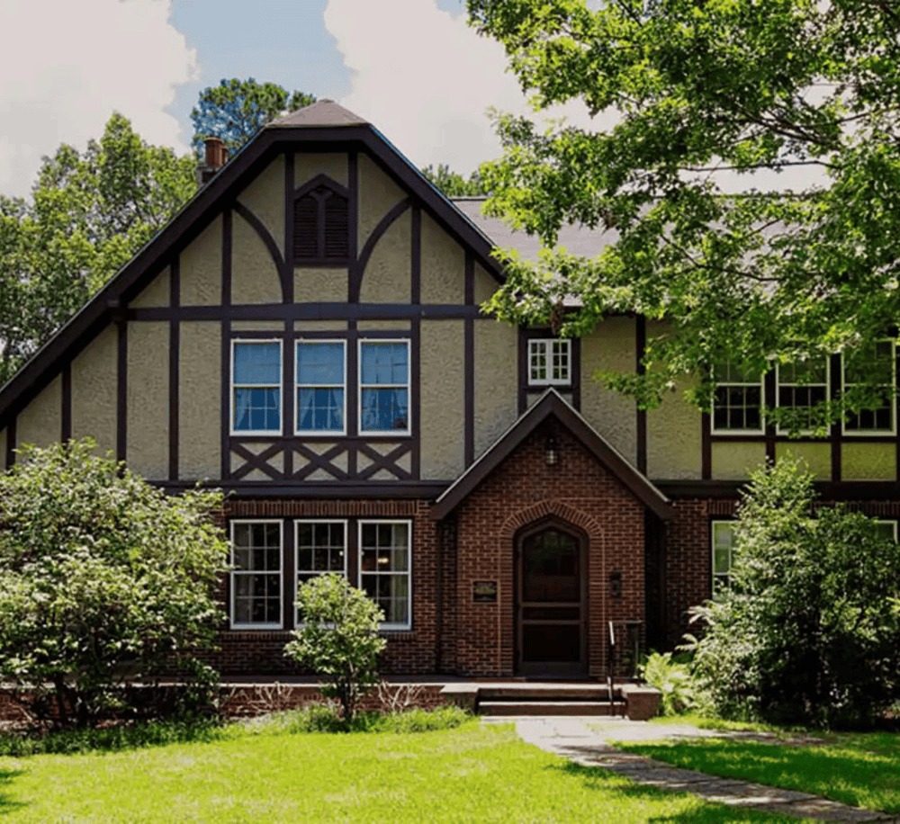 Charming Tudor-style home with lush greenery, perfect for real estate and property search.
