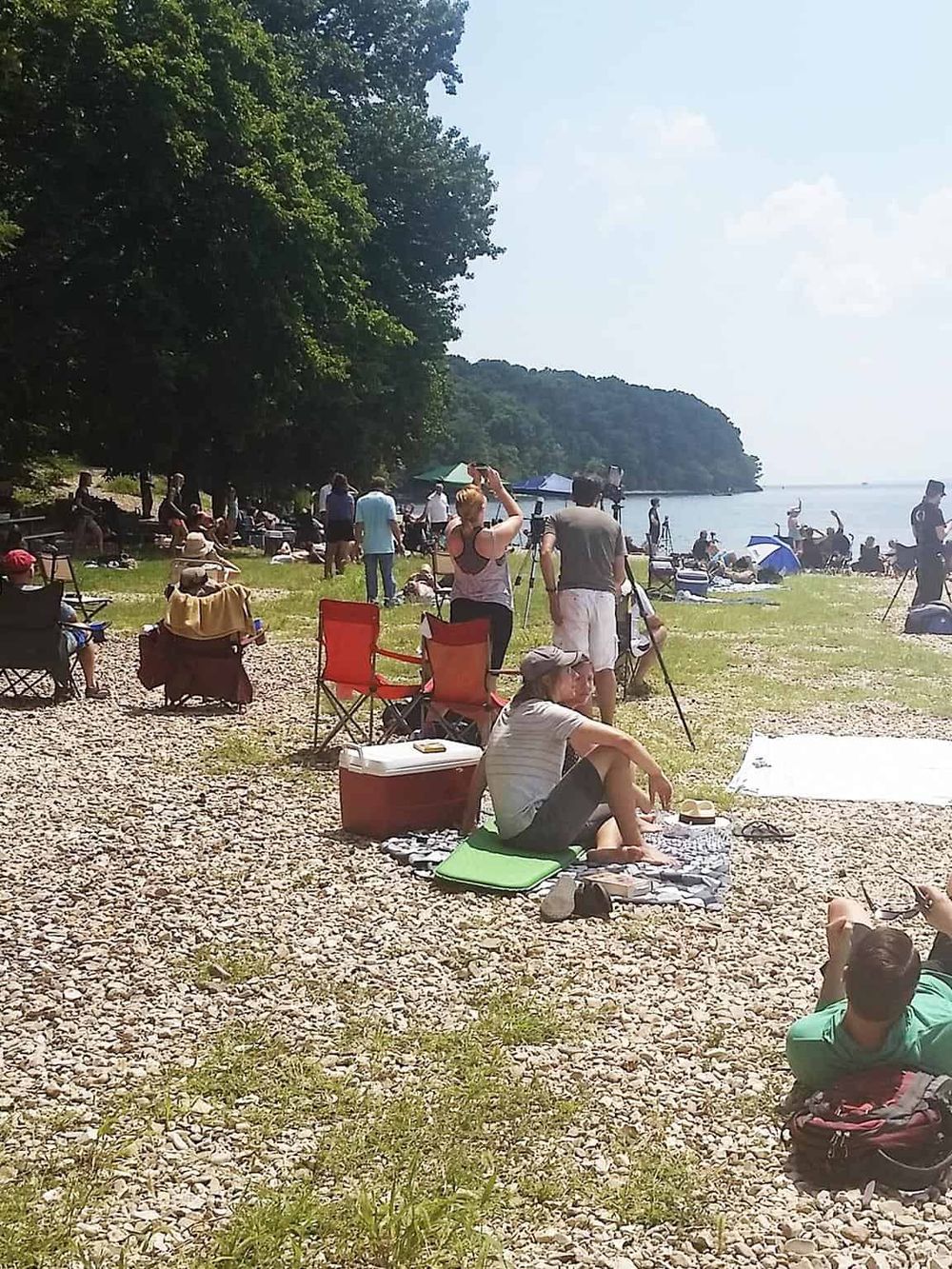 Relaxing lakeside scenery with people enjoying nature, capturing photos, and relaxing on a sunny day.