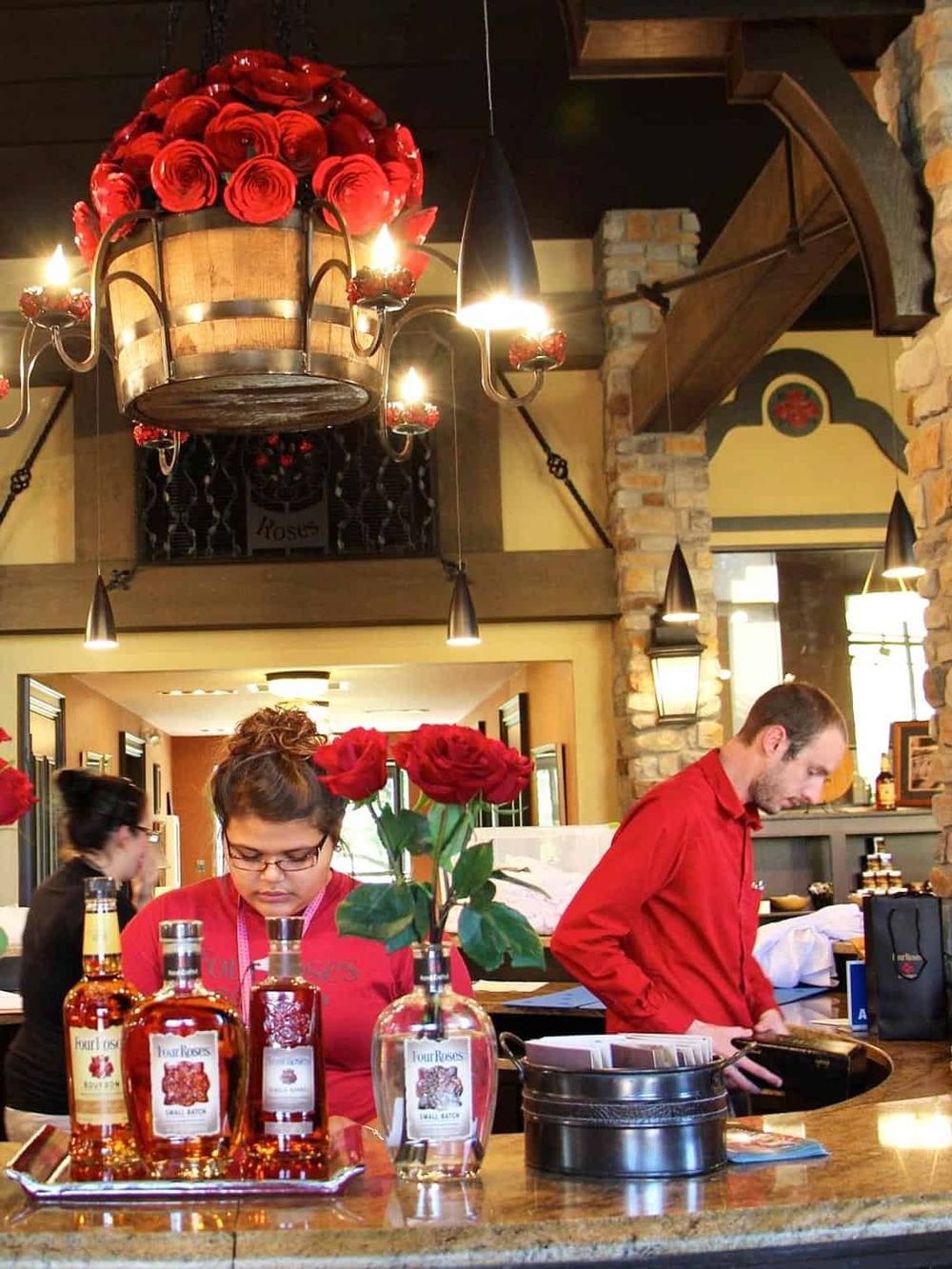 Vibrant bar scene with bartenders, roses, and warm lighting at a cozy restaurant.