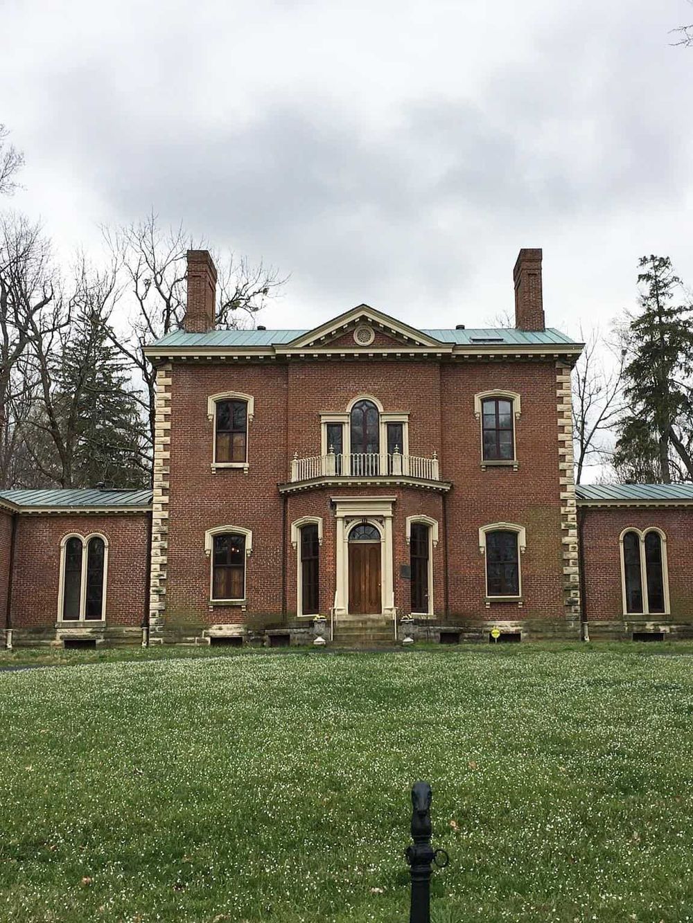 Elegant historic mansion with brick facade and lush green lawn, perfect for events and guided tours.