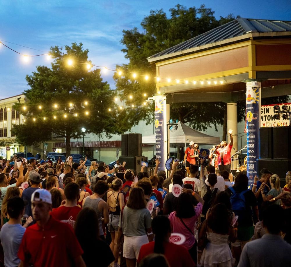 Vibrant outdoor concert at QuestForDirections event with lively crowd, stage, and string lights during evening.