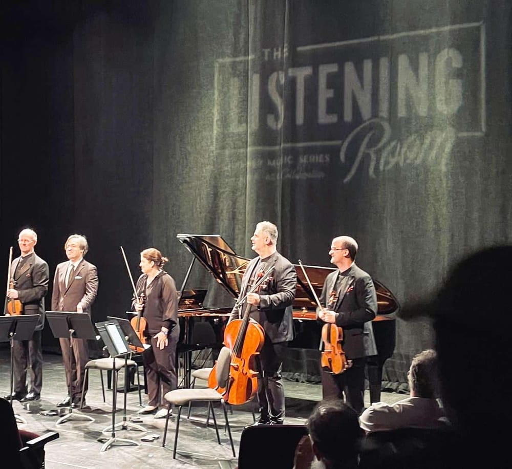 1. Acoustic musicians on stage with string instruments and a grand piano at a live concert event.