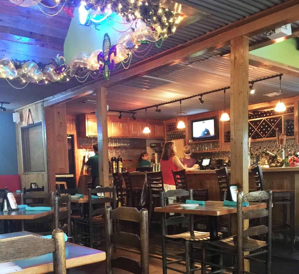 Cozy restaurant interior with decorated ceiling, wooden furniture, and patrons watching TV, creating a warm dining atmosphere.