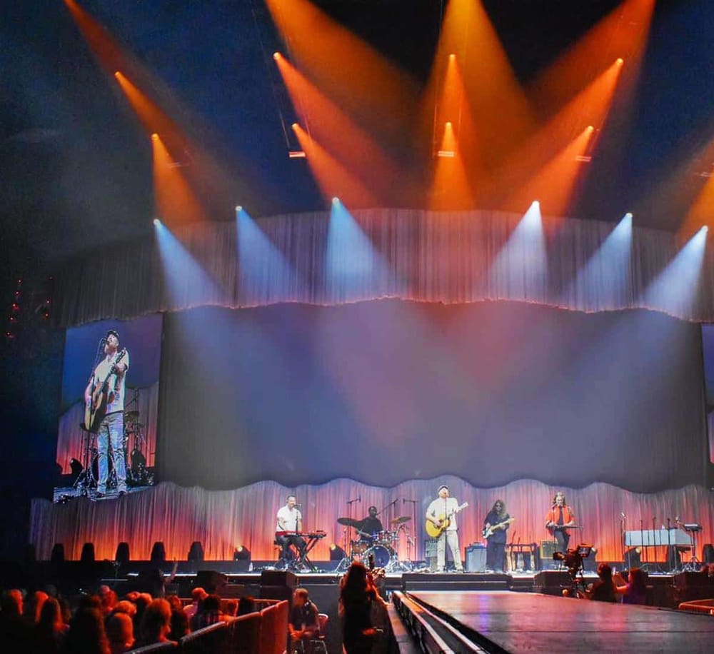 Bright stage lighting at a live music concert with a band, showcasing QuestForDirections event venue.