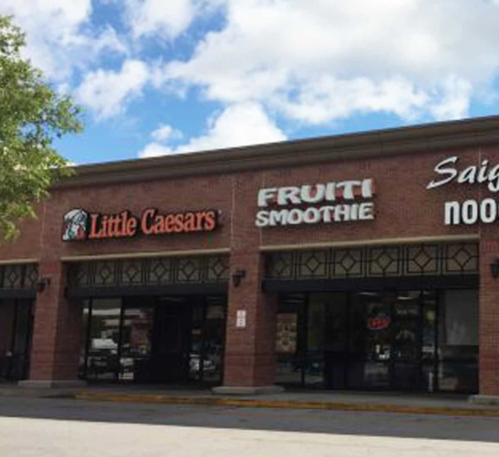 Fast food restaurant Little Caesars with fruit smoothies in shopping plaza, sunny day, roadside signage.