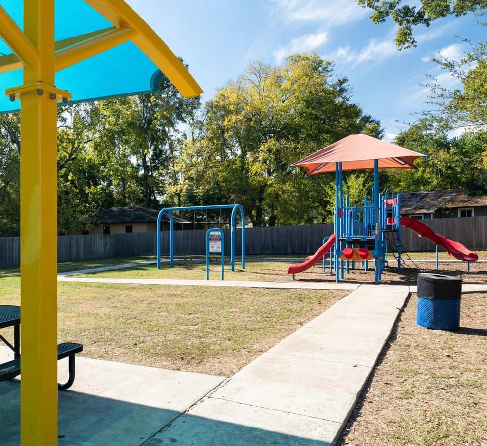 Colorful playground with slides and swings in a sunny park setting.