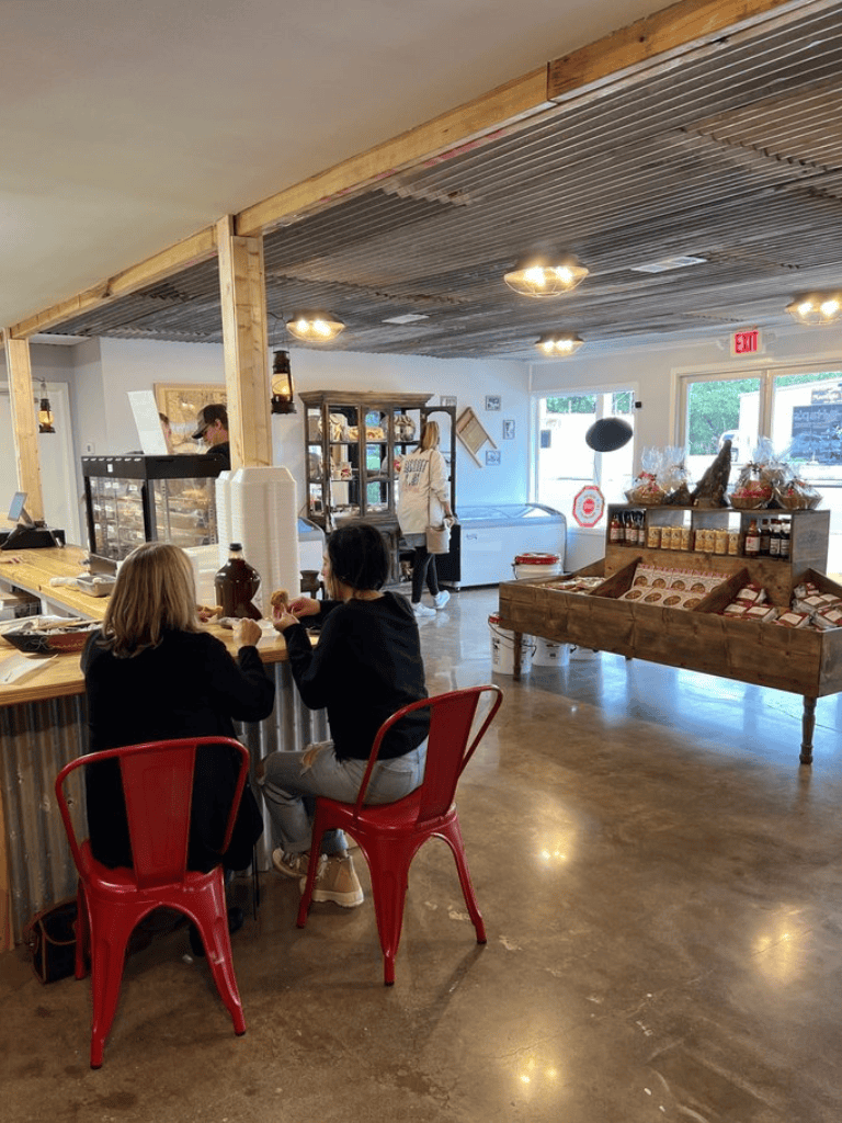 Cozy coffee shop interior with customers enjoying beverages, rustic decor, and natural light.