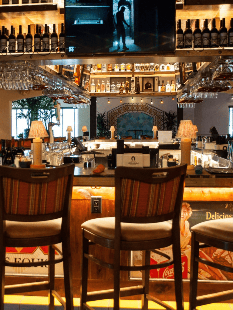 Cozy bar interior with warm lighting, bar counter, and decorative bottles, creating inviting ambiance for drinks and socializing.