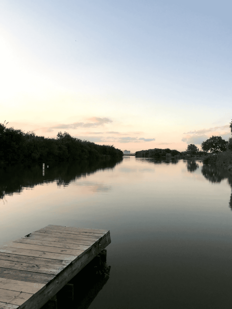 Peaceful waterway at sunset with a dock, perfect for exploring waterways with Quest For Directions.