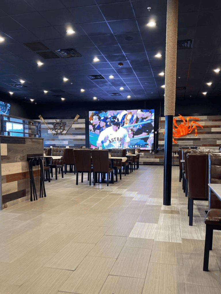 Watching baseball game on large TV at Quest For Directions restaurant interior with nautical decor.
