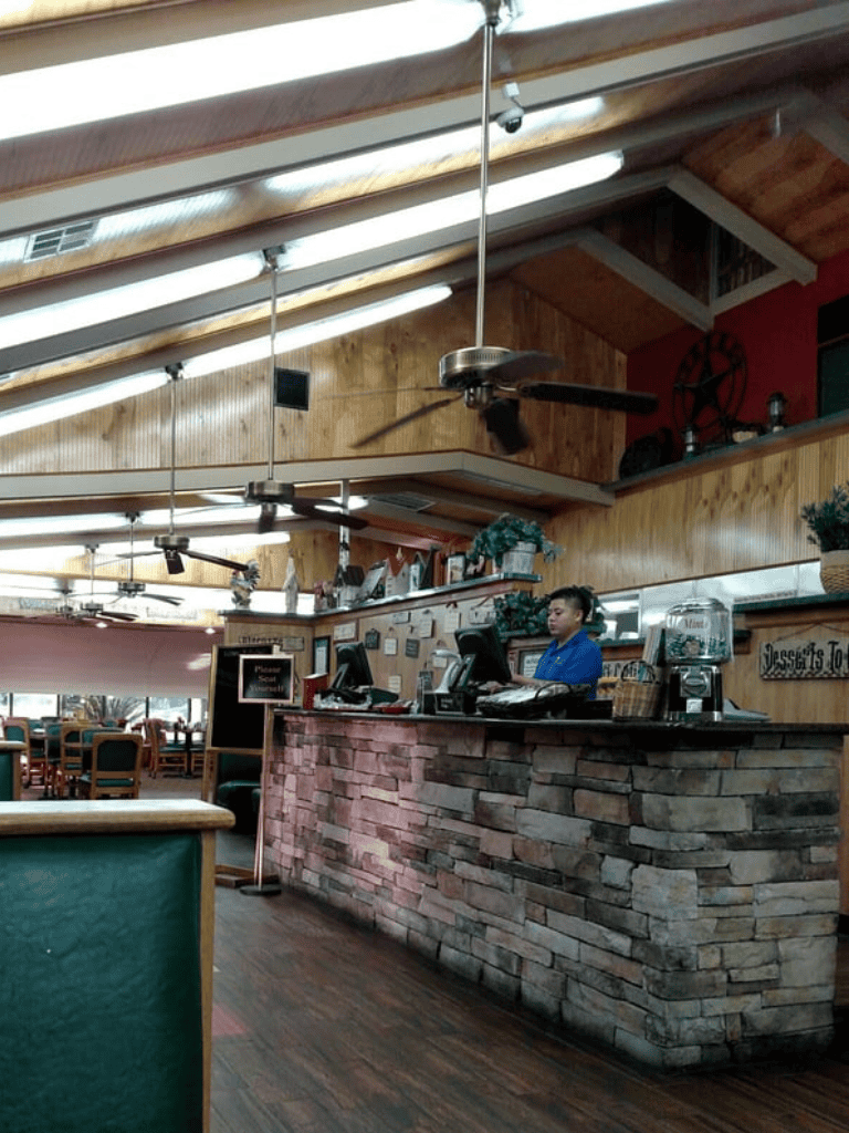 Cozy restaurant reception area with wooden accents and staff working at the counter.