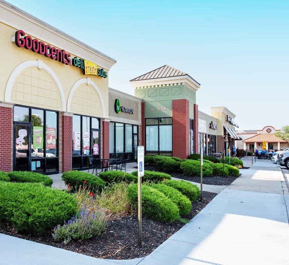 Vibrant shopping plaza featuring QuestForDirections store with outdoor seating and lush landscaping.