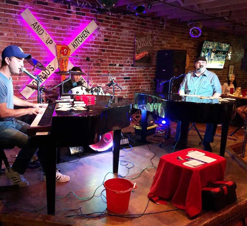Live music performance at a cozy restaurant with brick walls and bar ambiance.