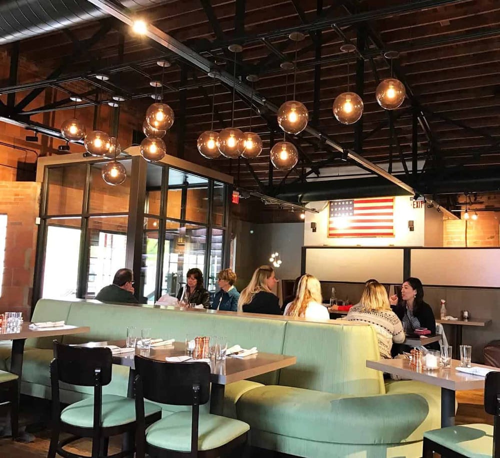 Bright modern restaurant interior with hanging Edison bulbs and American flag decor, ideal for dining and social gatherings.