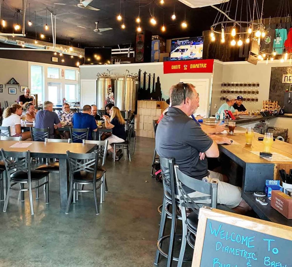 1. Cozy brewery interior with patrons enjoying drinks and TV sports viewing.