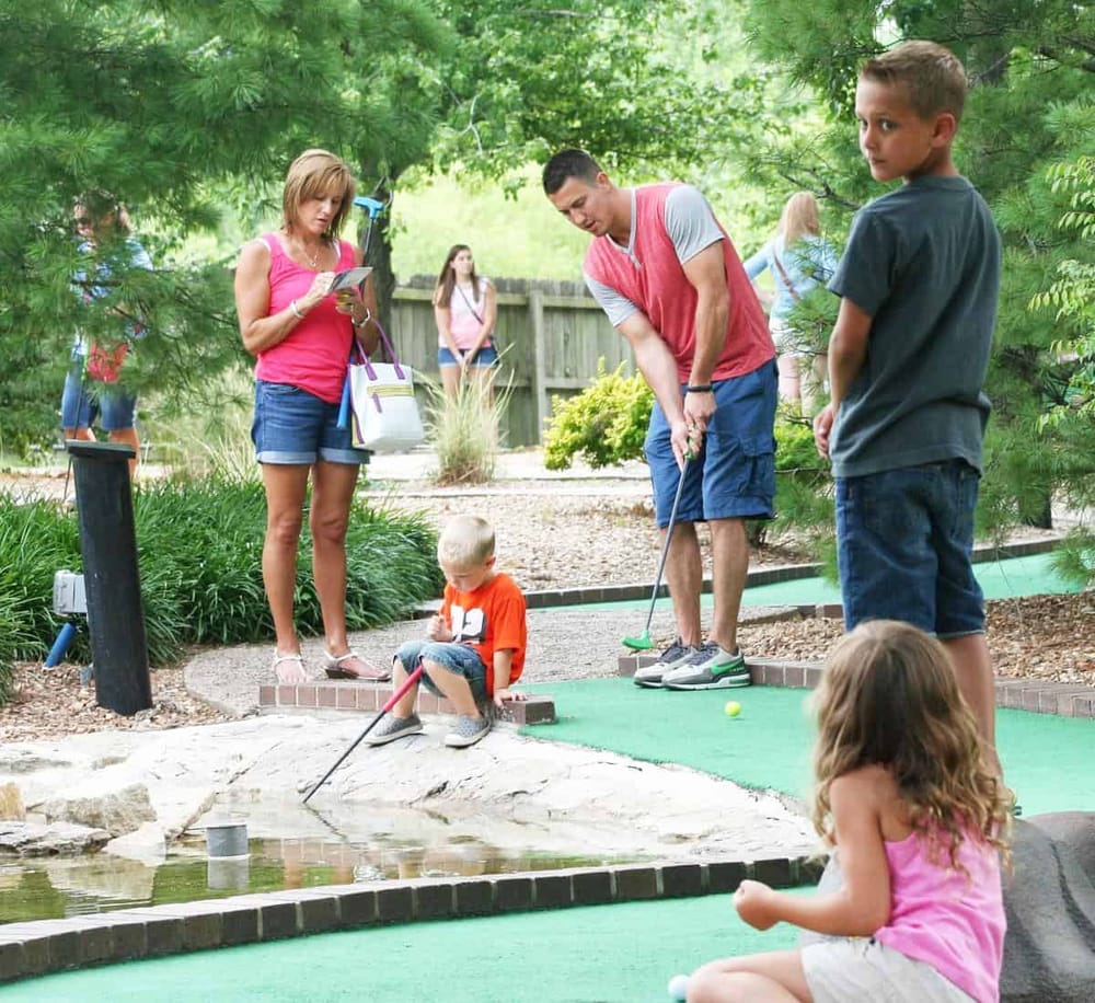 1. People enjoying mini golf game outdoors at Quest for Directions.