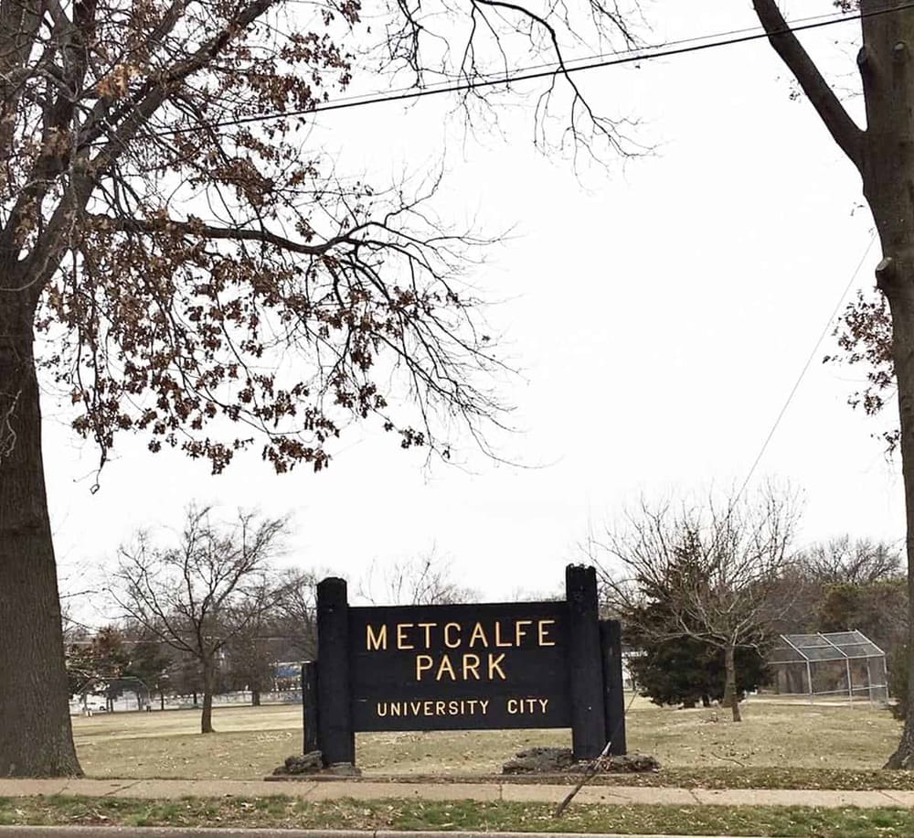 Spacious park at Metcalfe Park in University City with trees and open field for outdoor activities.