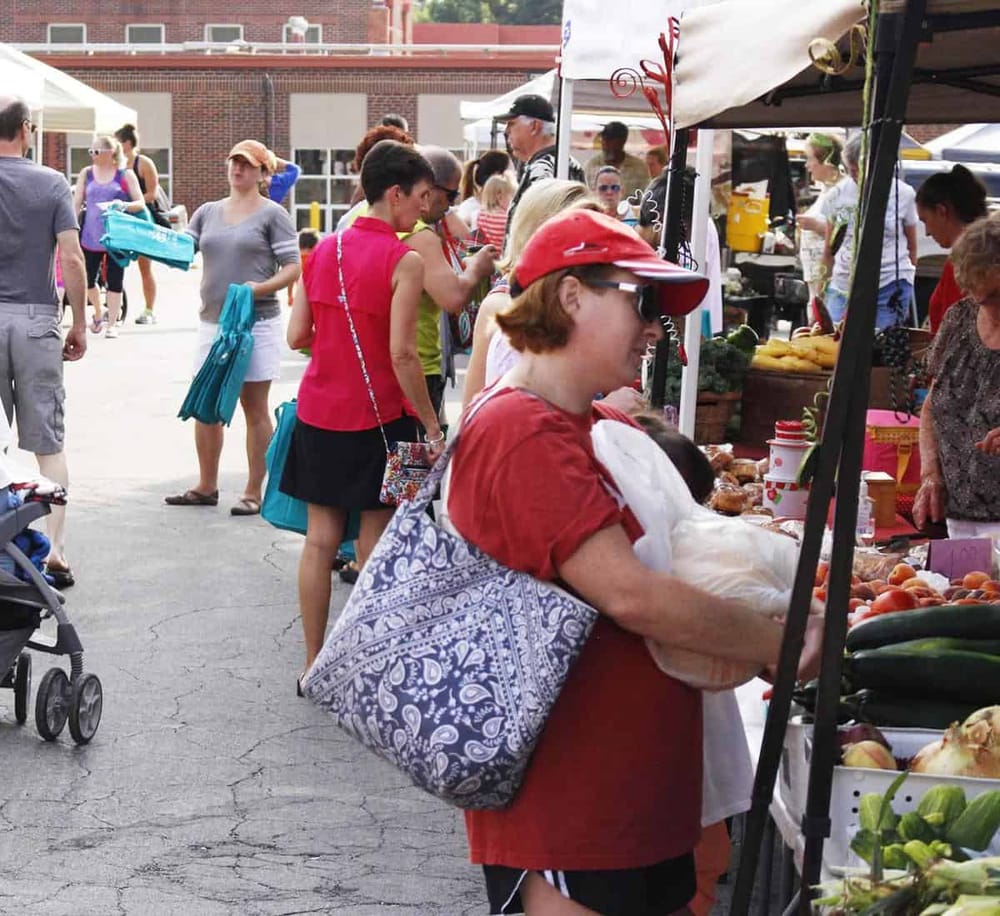 Colorful outdoor farmers market busy with shoppers and vendors, fresh produce, community event, local food shop.