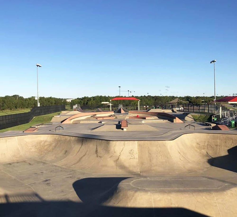 Skatepark with ramps and bowls under clear blue sky, popular outdoor recreational skateboarding spot.