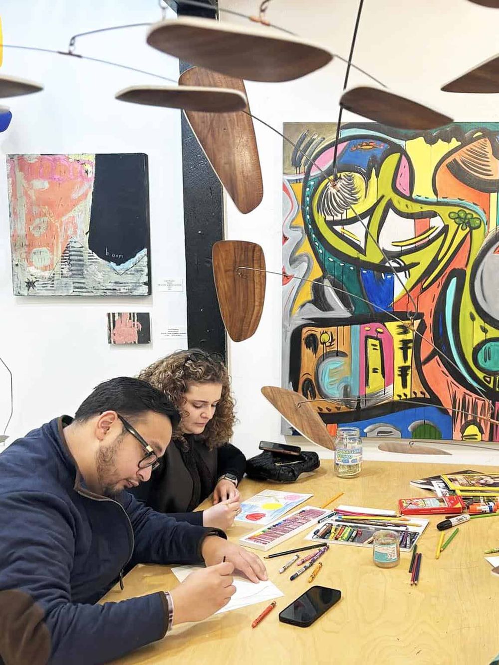 Colorful art space with artists creating vibrant artworks, blending creativity and inspiration in a modern gallery setting.