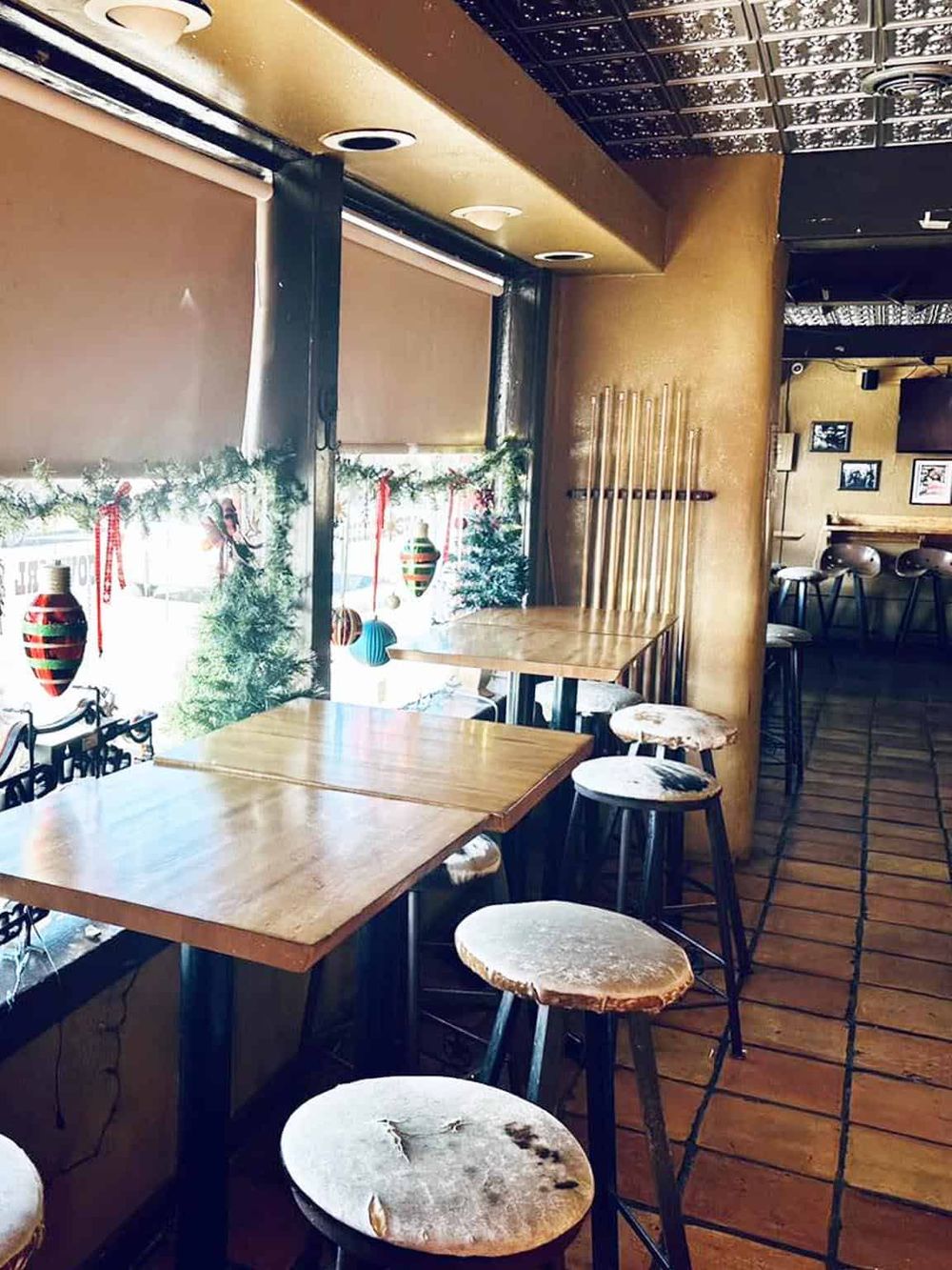 Cozy cafe interior with wooden tables, bar stools, and Christmas decorations, perfect for a relaxing visit.