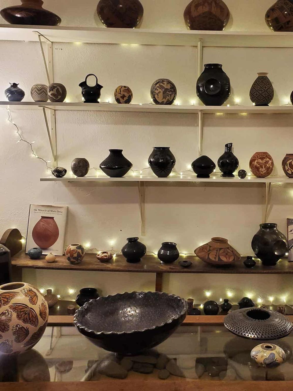 Vase display with handcrafted pottery and decorative items in a gallery setting.