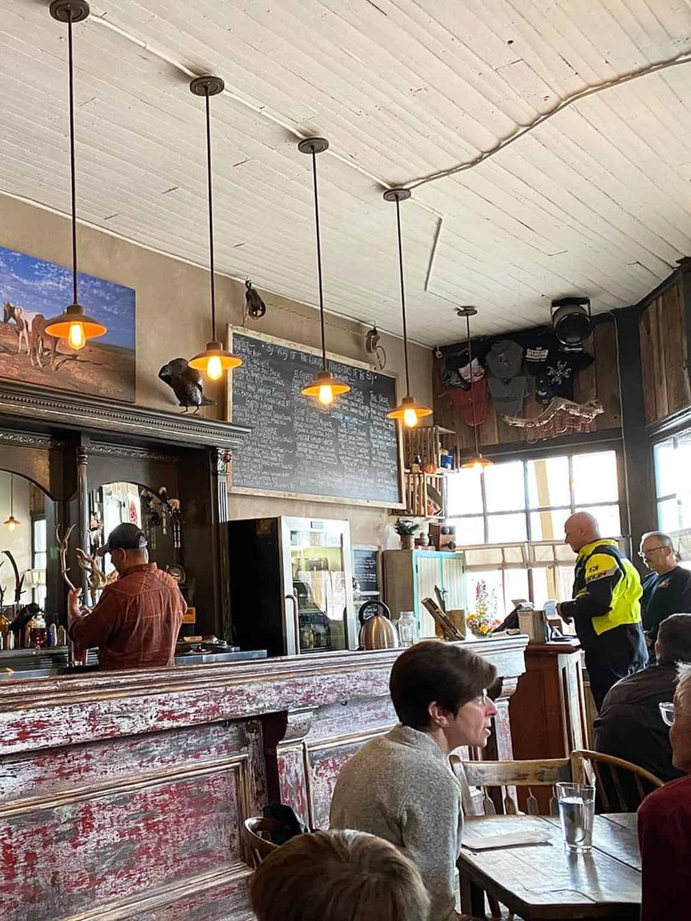 Cozy café interior with patrons, rustic decor, menu chalkboard, and warm lighting at QuestForDirections.