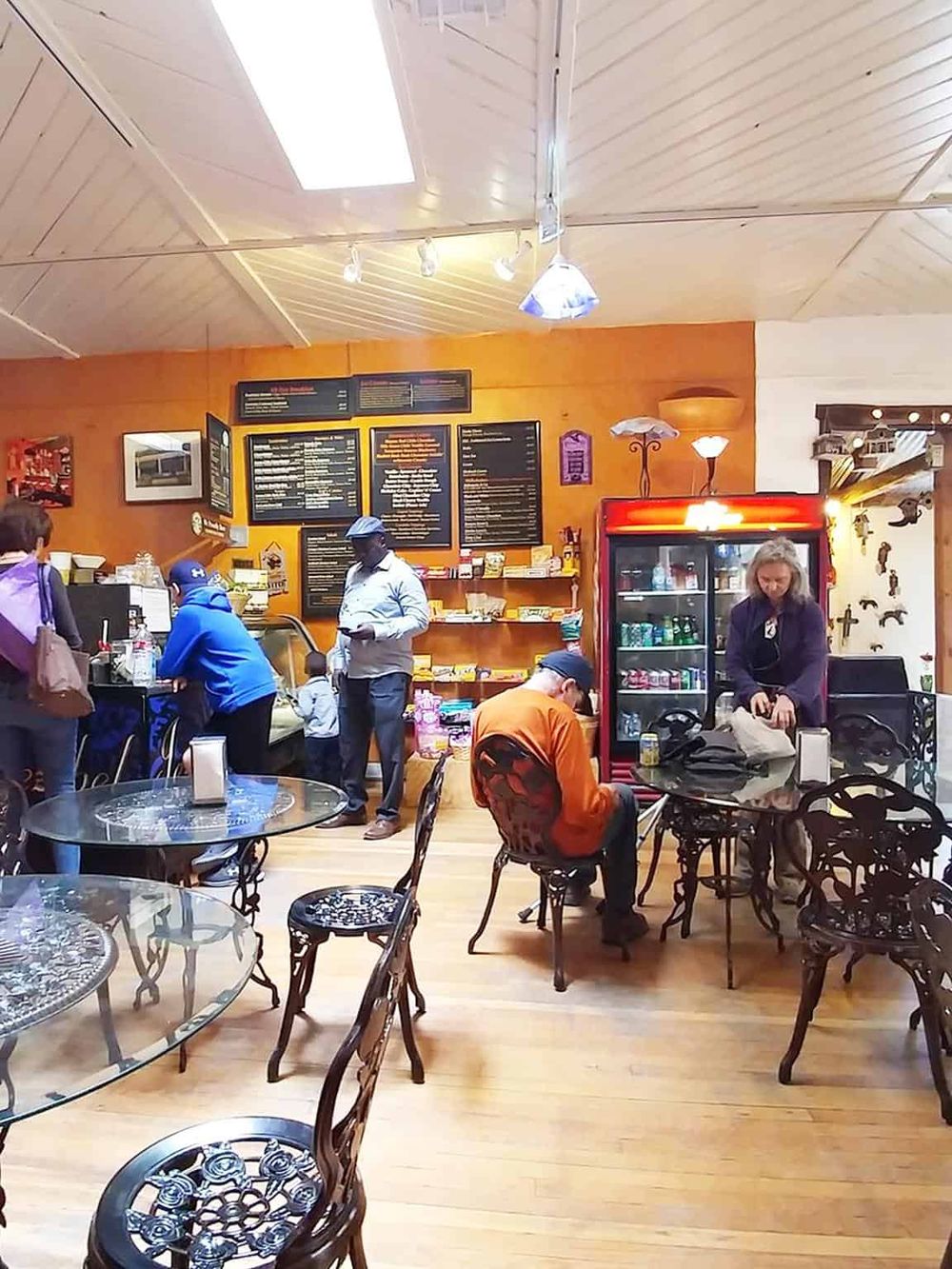 Cozy cafe interior with customers enjoying food and drinks, warm lighting, and a vibrant menu board, perfect for a travel-friendly cafe experience.