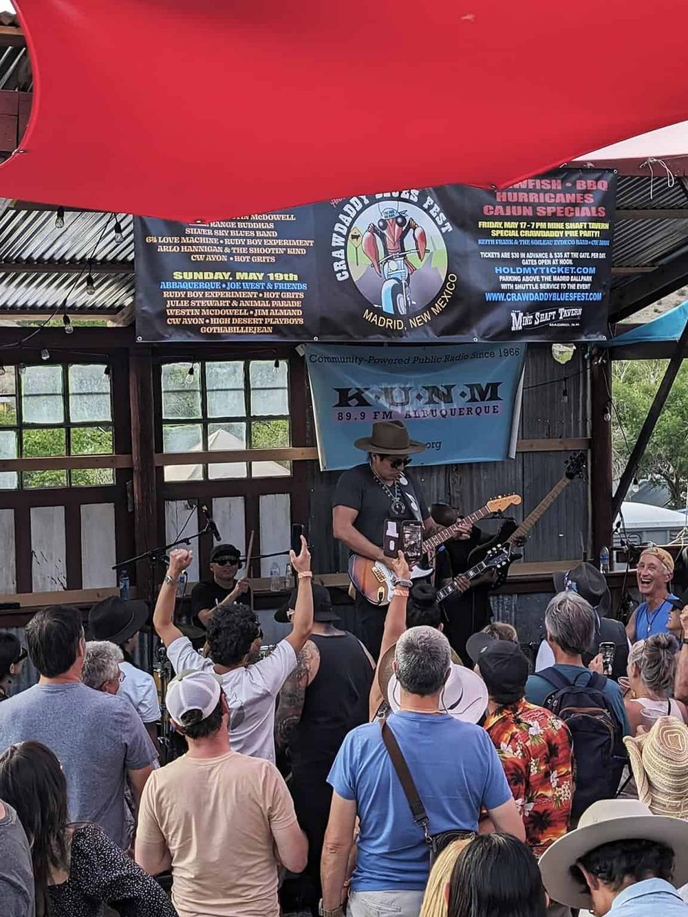 Live outdoor concert featuring guitarists and a cheerful crowd at a music festival in Madrid, New Mexico.