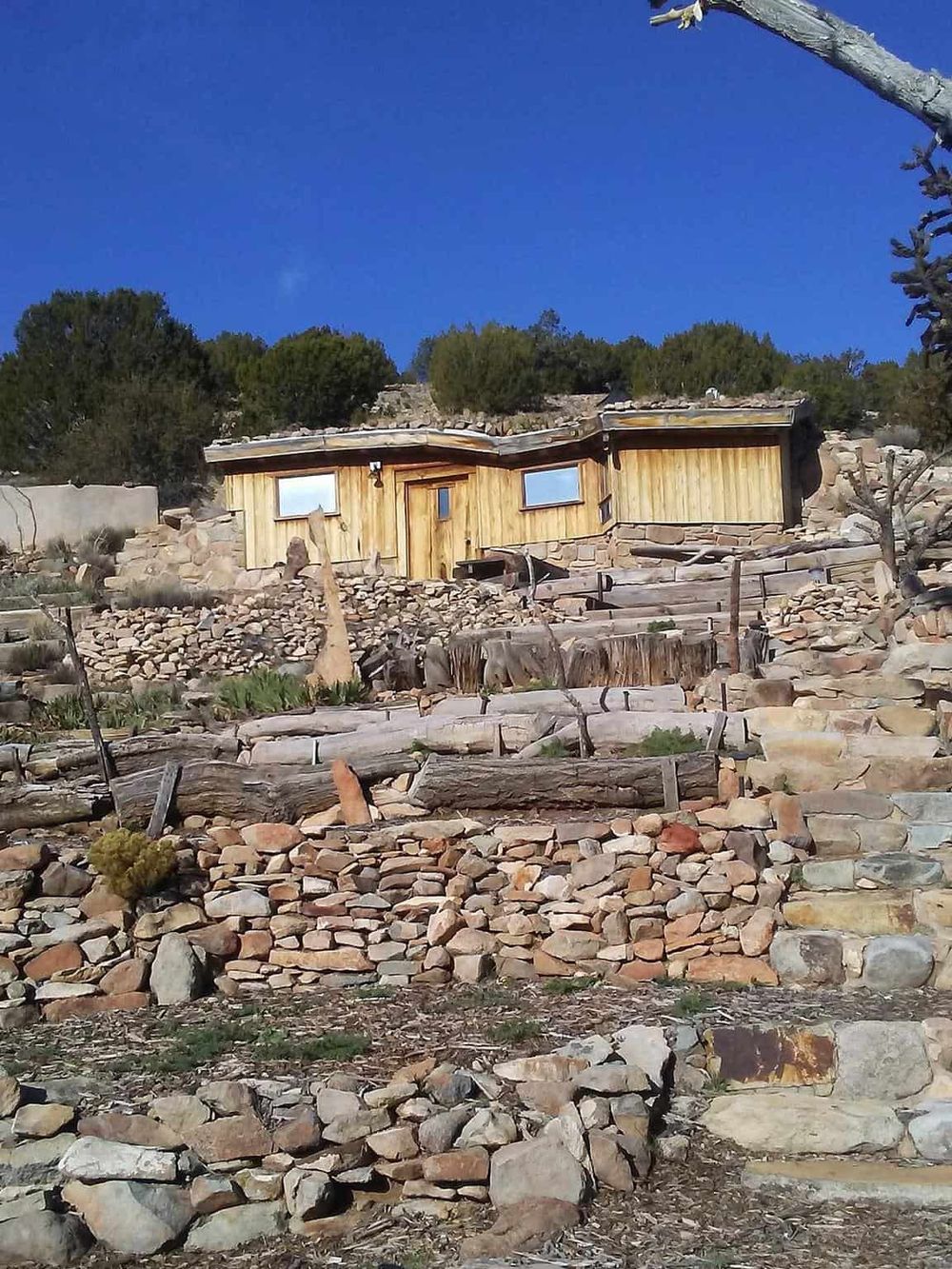 Rustic mountain cabin with stone and wood accents, surrounded by natural landscape, ideal for outdoor adventure retreats.