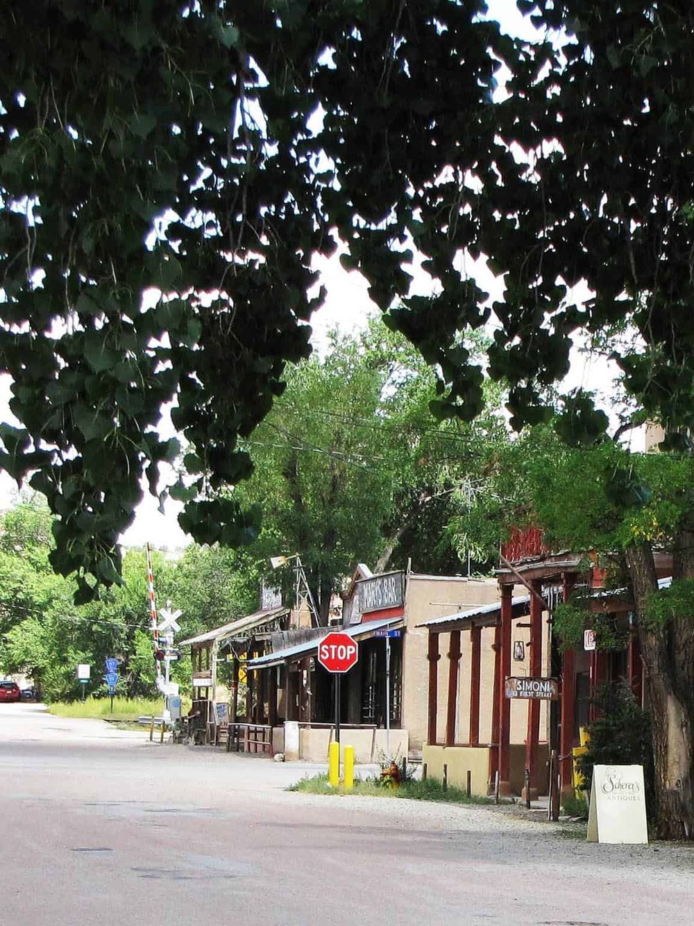 Charming small-town street view with local shops, stop sign, and lush trees, perfect for travel and exploration.