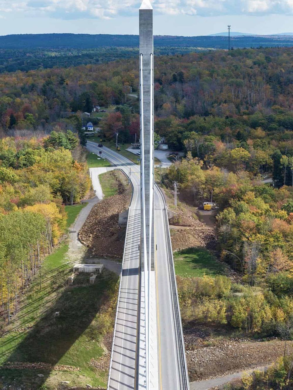 High-angle view of a bridge over a lush, colorful fall landscape, highlighting engineering marvels and scenic beauty.