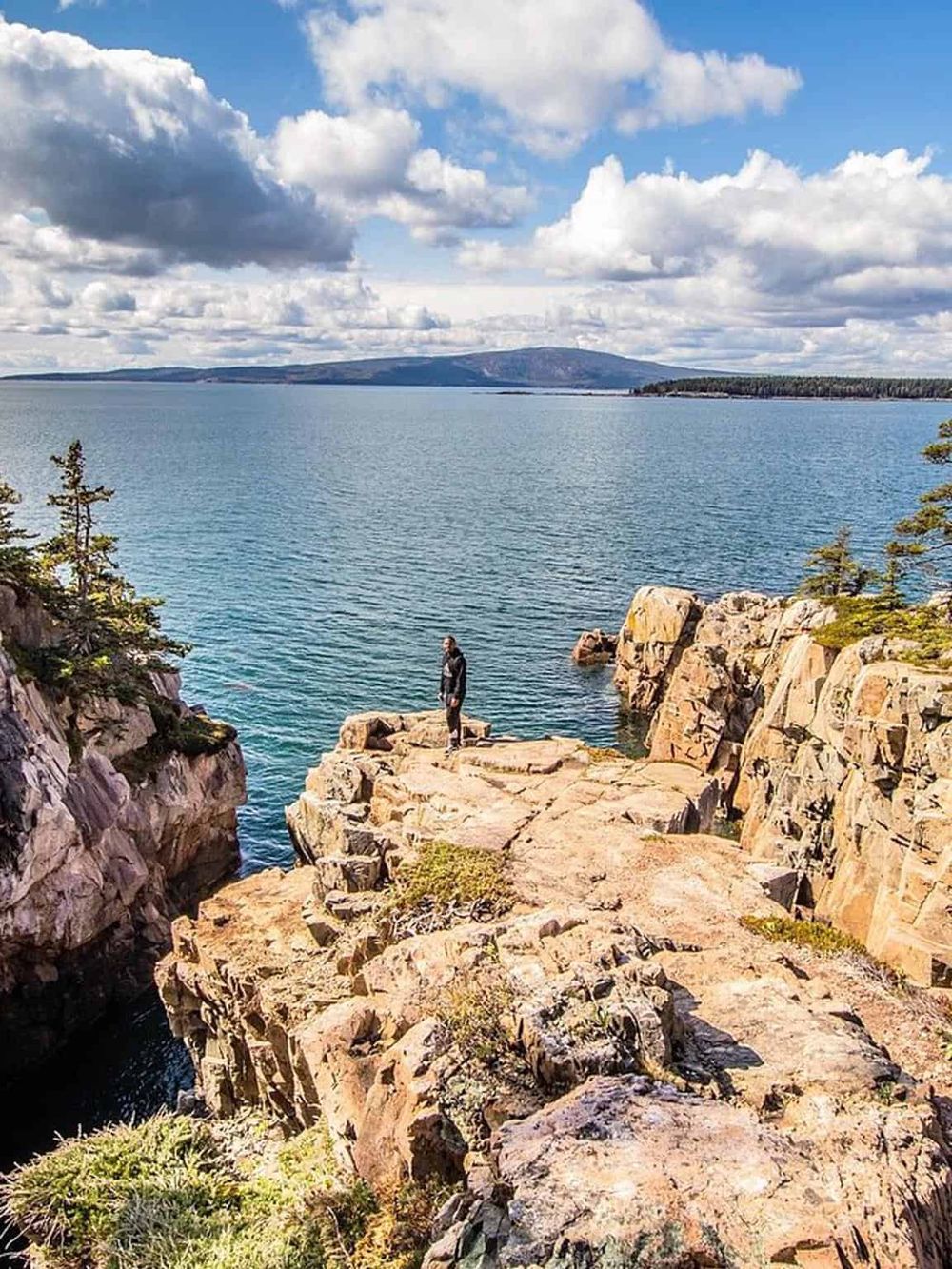 Serene lake view with rocky shoreline and person enjoying nature, perfect for outdoor adventure and travel destinations.