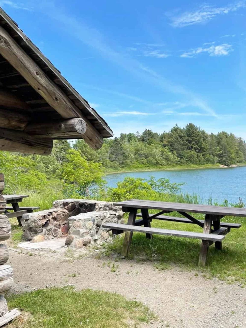 Tranquil lakeside picnic area with rustic shelter, outdoor benches, and scenic nature views, ideal for relaxation and outdoor recreation.