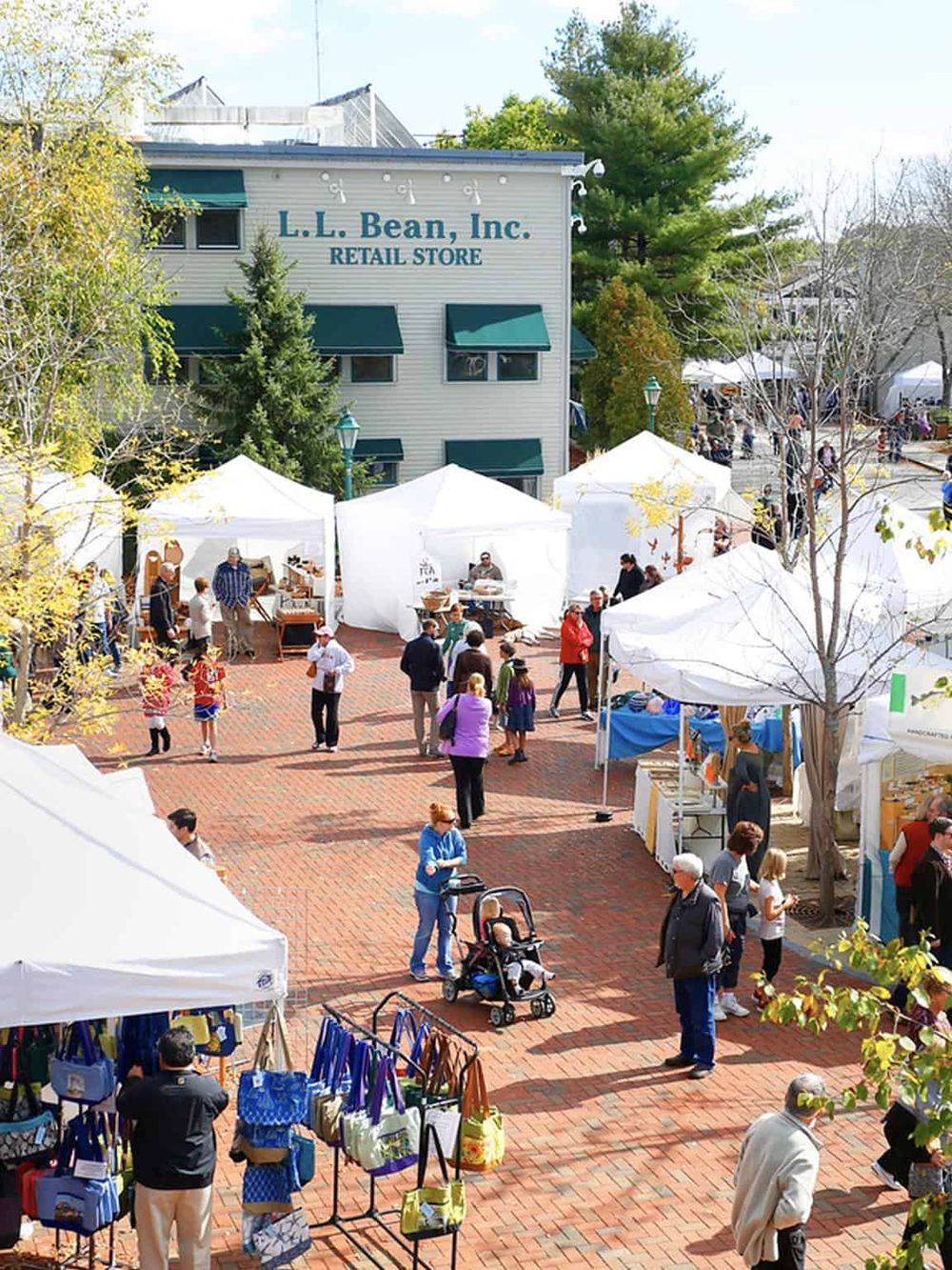 Colorful outdoor market at QuestForDirections event with tents, shoppers, and retail stores.