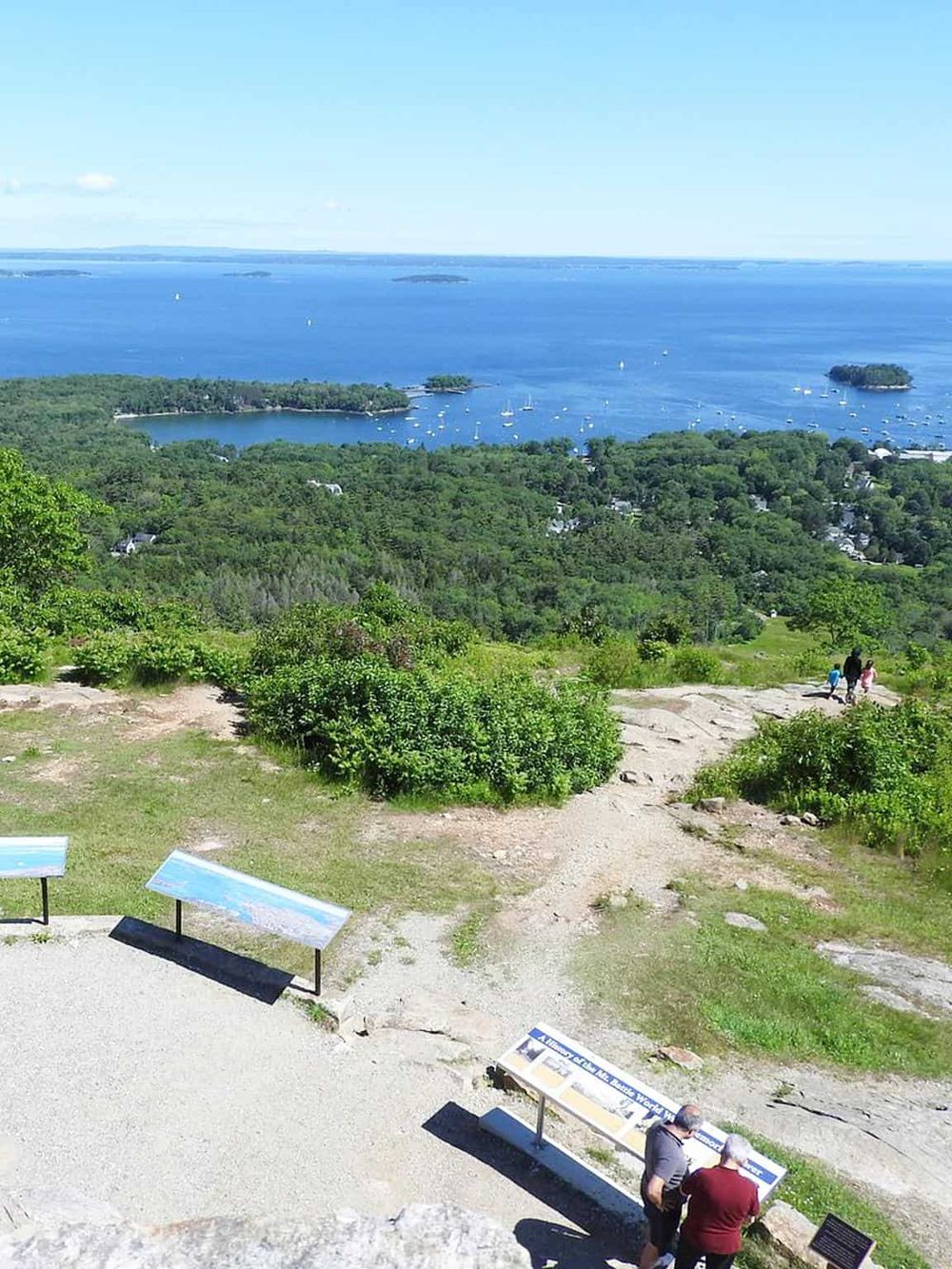 Breathtaking view of a scenic harbor with boats, greenery, and blue waters from a lookout point.