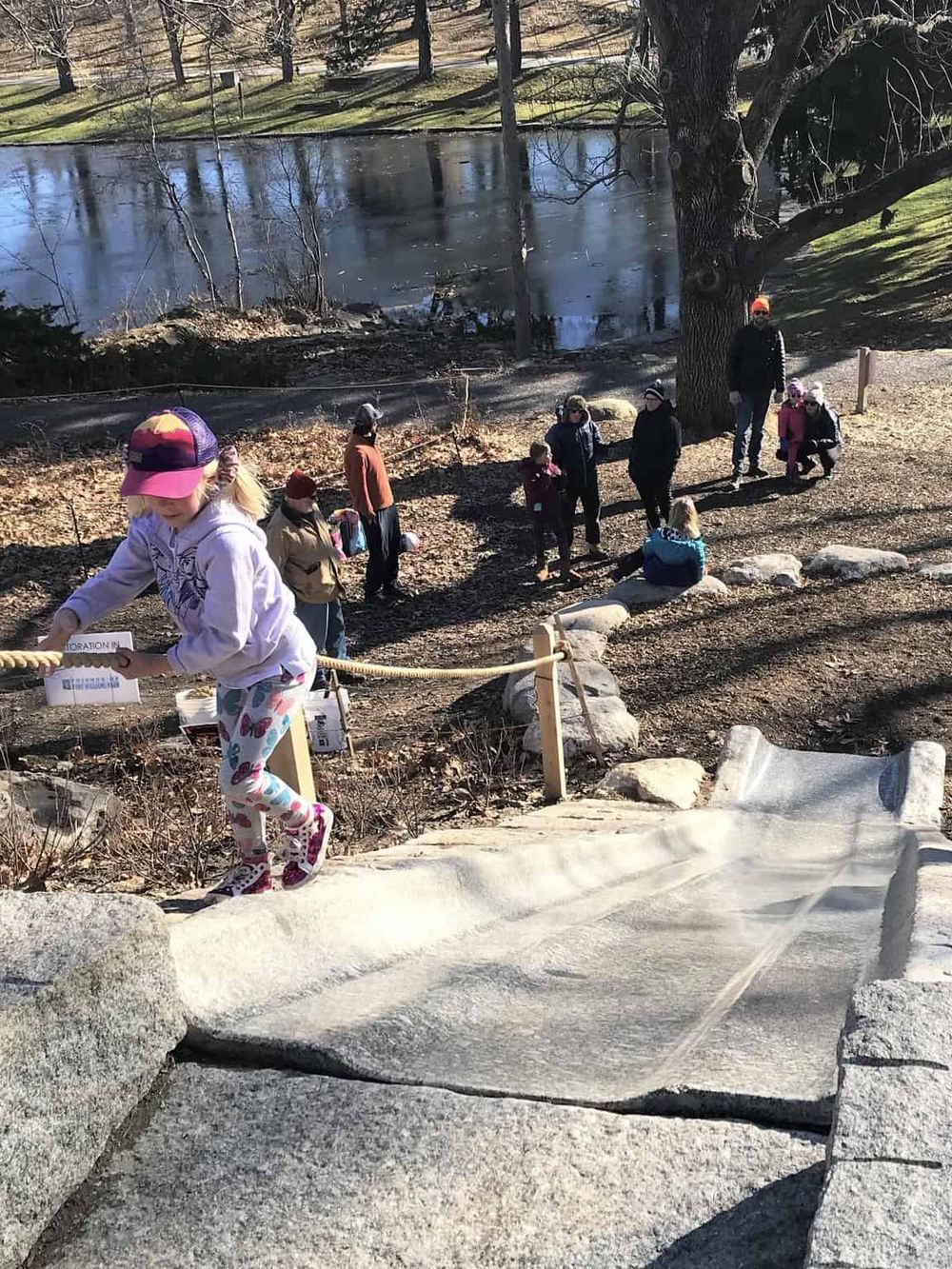 Children and families enjoying outdoor activities at QuestForDirections park site. Engaged in group exploration near the pond.